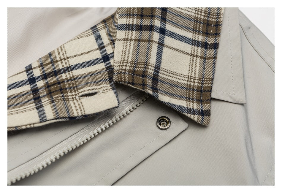 Close-up of a beige and navy plaid collar, light gray fabric, zipper, and snap closure.