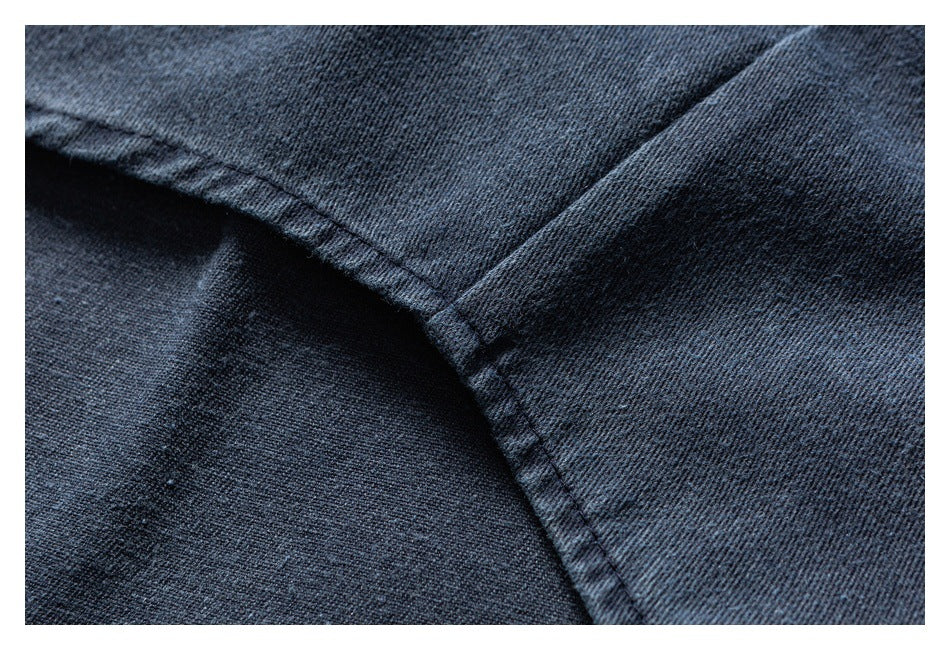 Close-up of dark blue denim with intersecting stitched seams and a folded fabric edge.