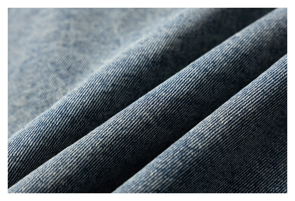 Close-up of blue denim fabric draped in folds, showing its diagonal weave and faded texture.
