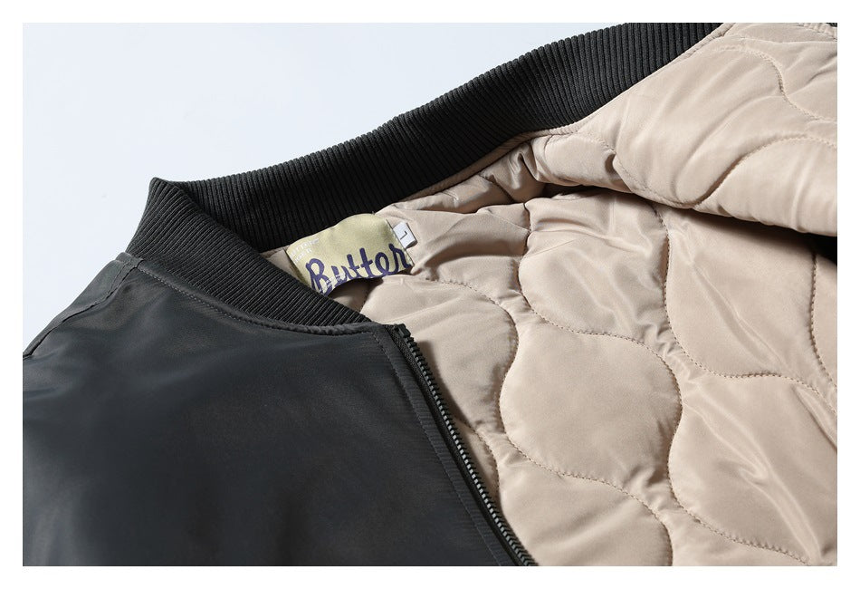 Close-up of a dark jacket collar, zipper, and beige quilted lining with an interior label.