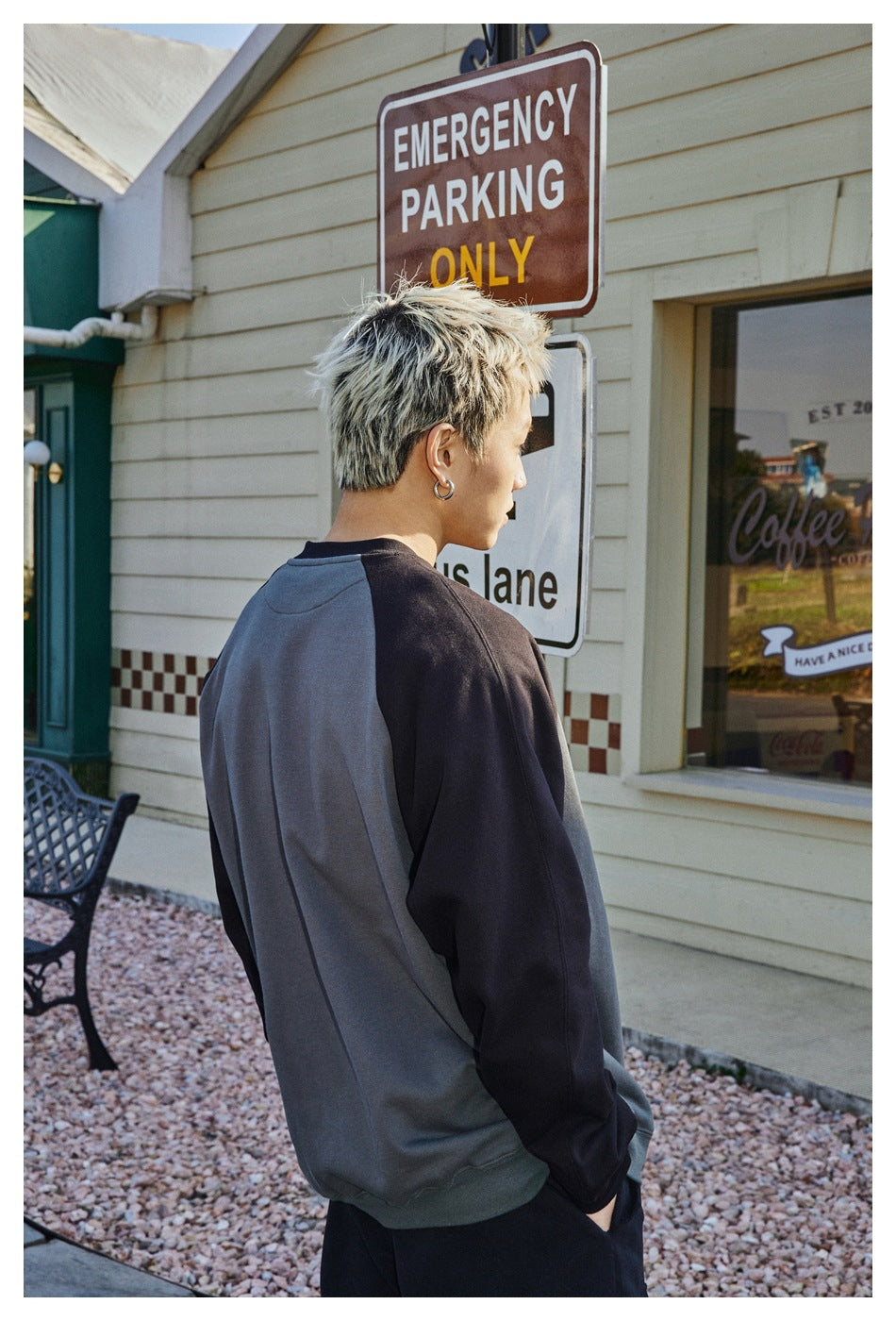 Rear view of a model wearing a charcoal sweatshirt with black raglan sleeves and a dark ribbed hem.