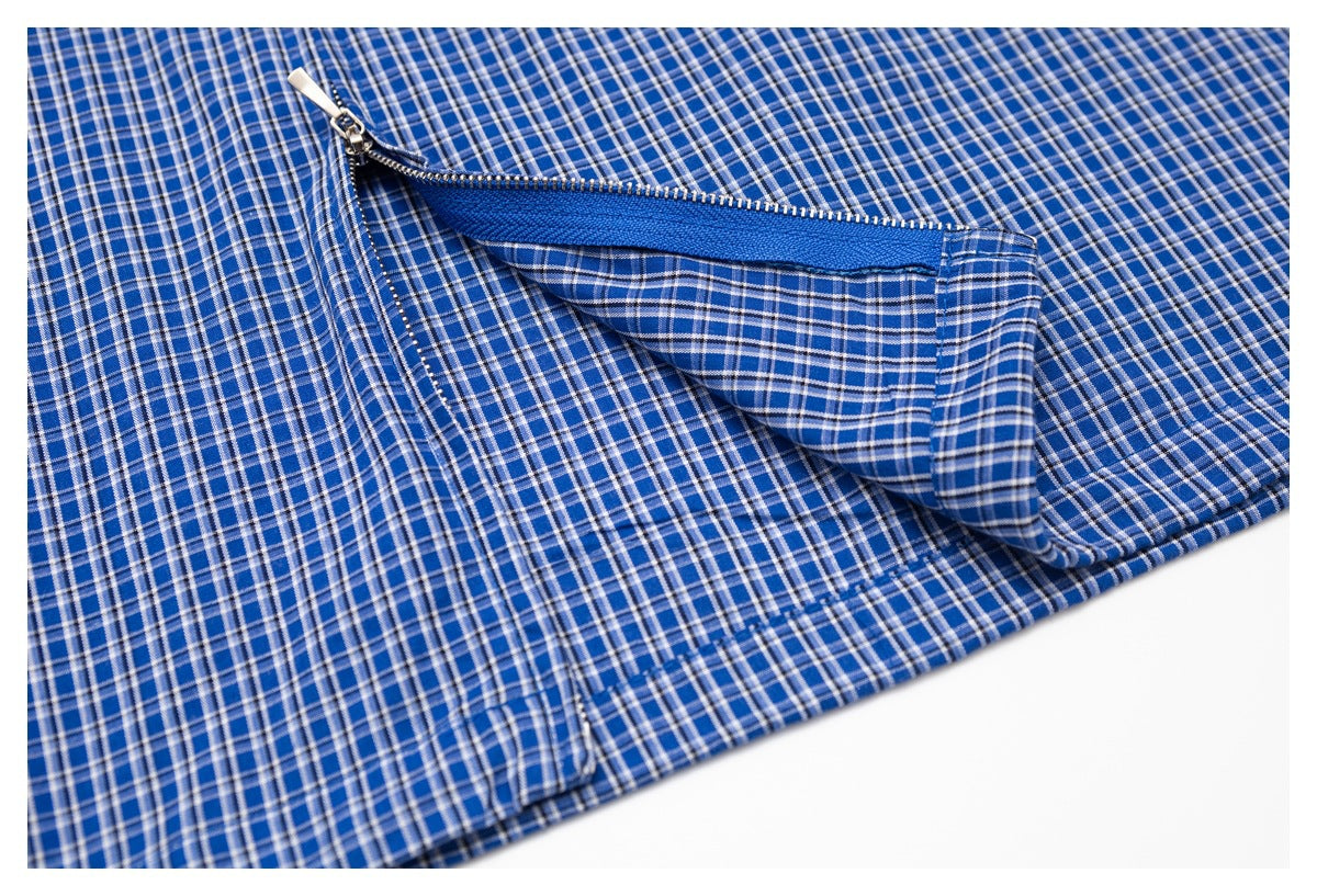 Blue plaid garment detail showing an open zipper pocket and stitched edge.