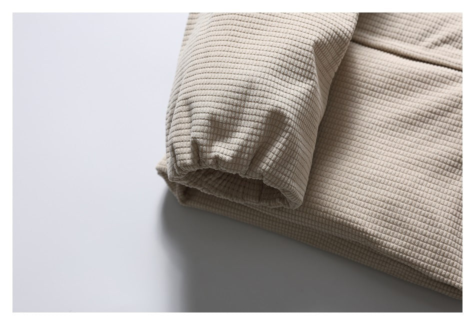 Close-up of the light beige jacket's gathered sleeve cuff and textured fabric.