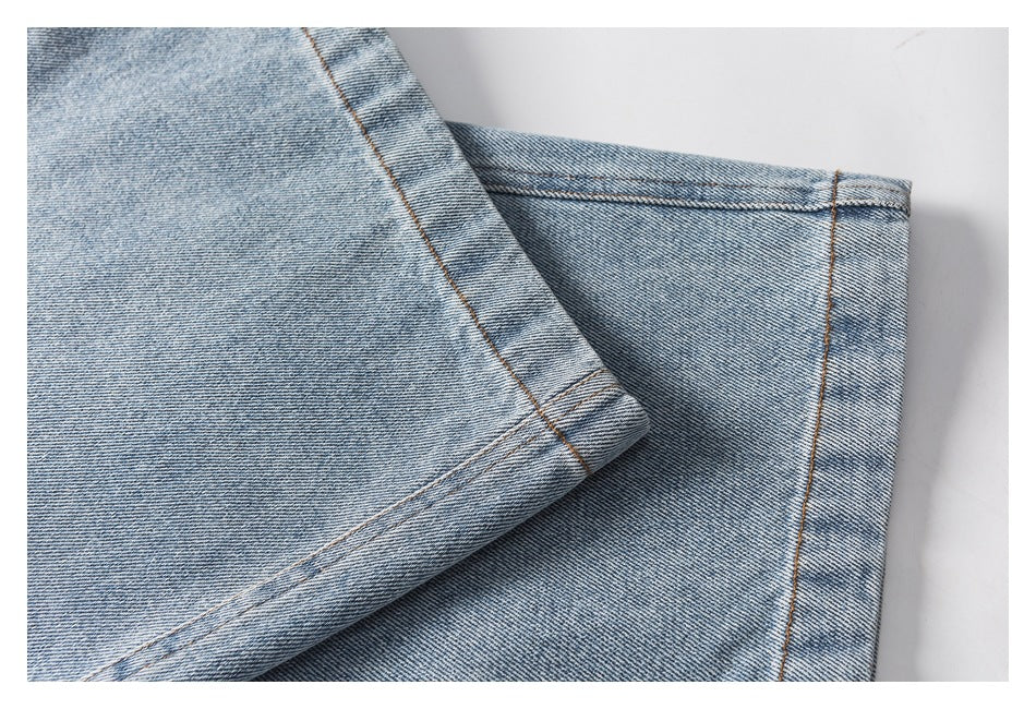 Close-up of light blue washed denim pant legs, showing the stitched hems and seams.