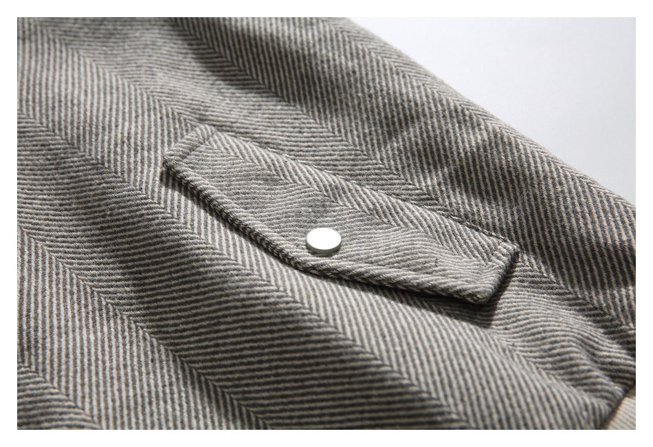 Close-up of a snap-button flap pocket on the jacket's gray herringbone fabric.