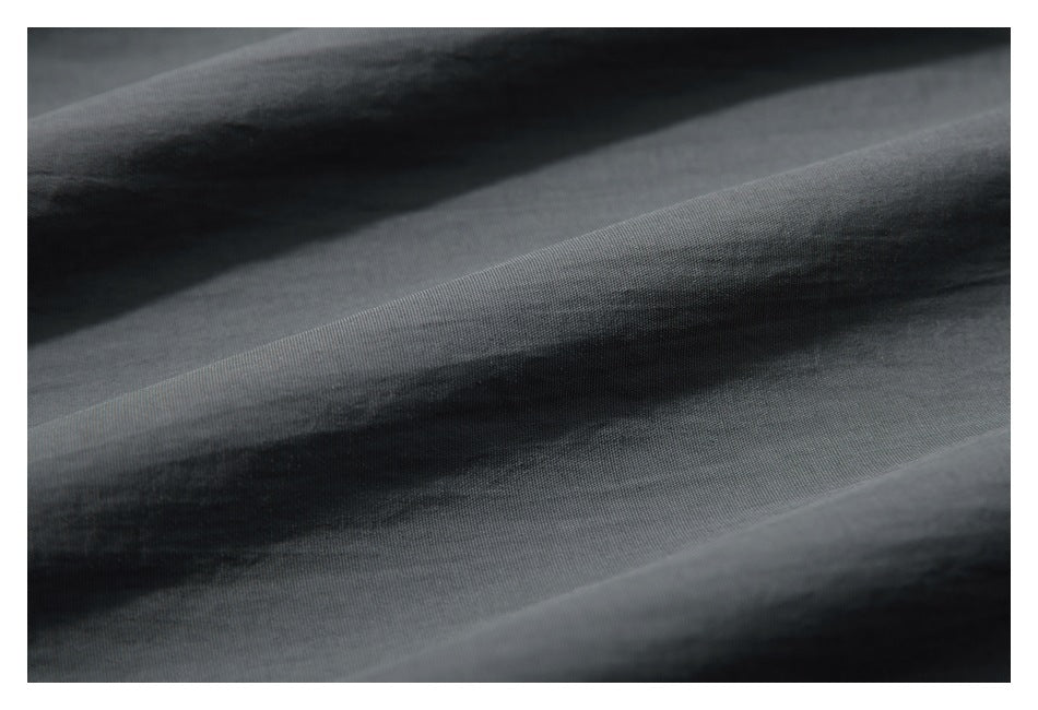 Extreme close-up of the charcoal-gray jacket fabric, showing its fine woven texture and folds.