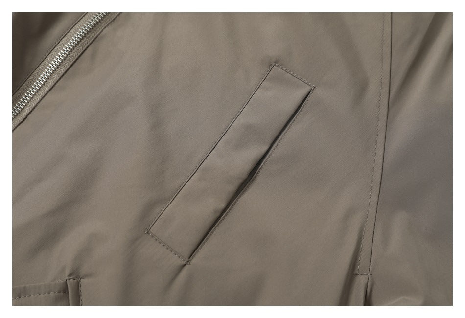 Close-up of a slanted welt pocket on the taupe jacket, with part of the zipper visible.