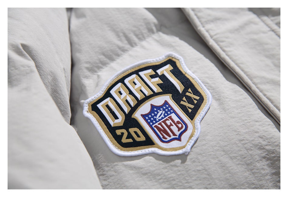 Close-up of a gold, black, and white embroidered football draft patch on the off-white jacket.