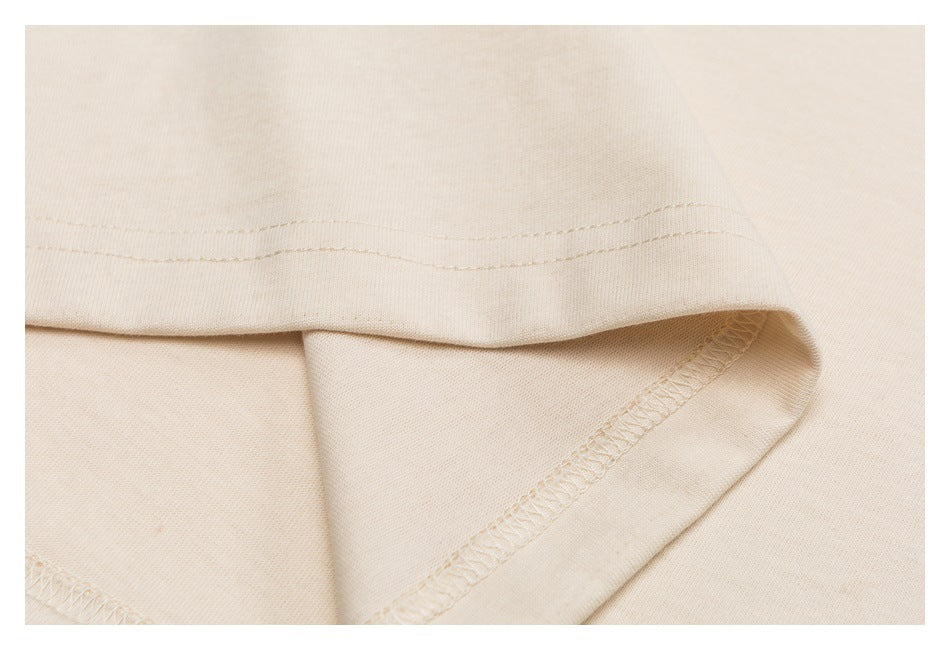 Close-up of the cream shirt hem, showing folded fabric and stitching.