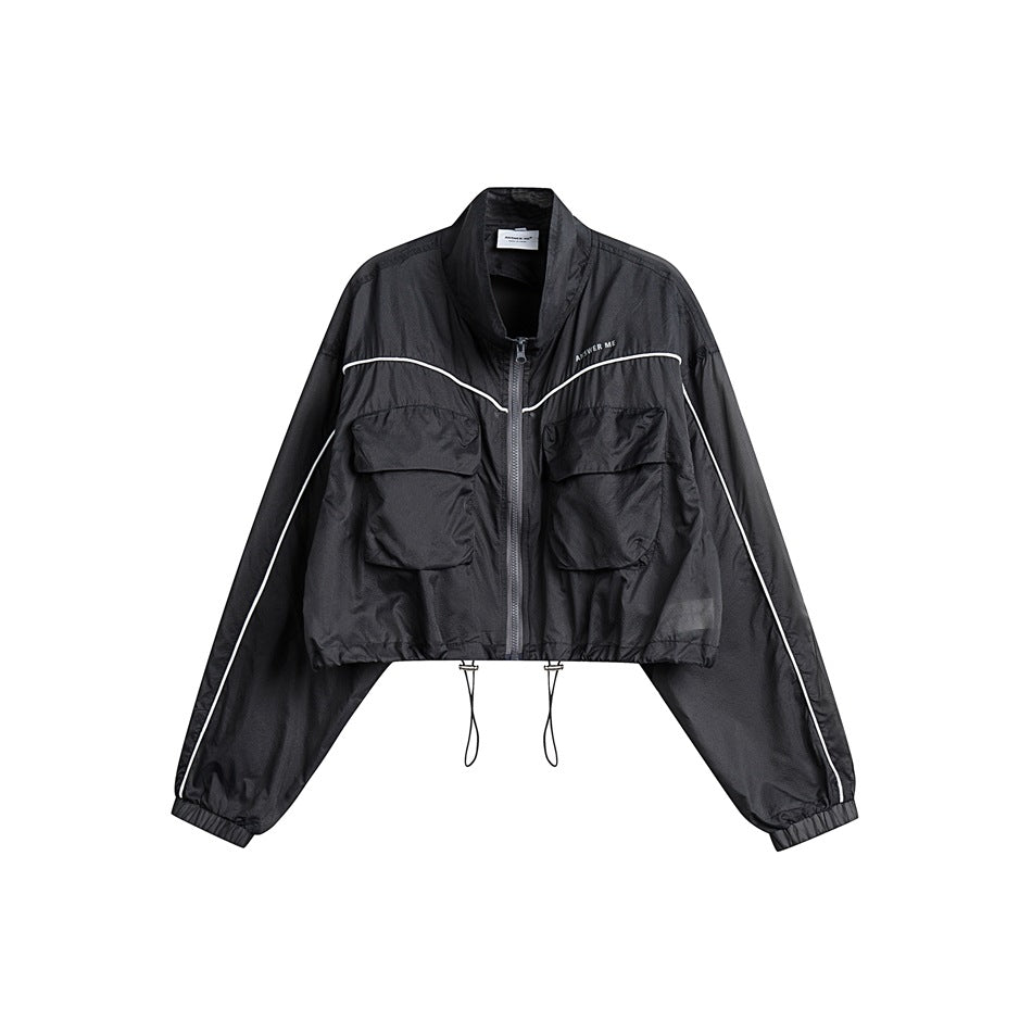 Front view of a black cropped jacket with a zip closure, flap pockets, white piping, and adjustable hem drawcords.