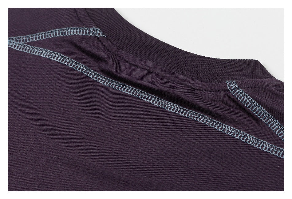 Close-up of a dark plum garment neckline and shoulder seams with contrasting light blue overlock stitching.