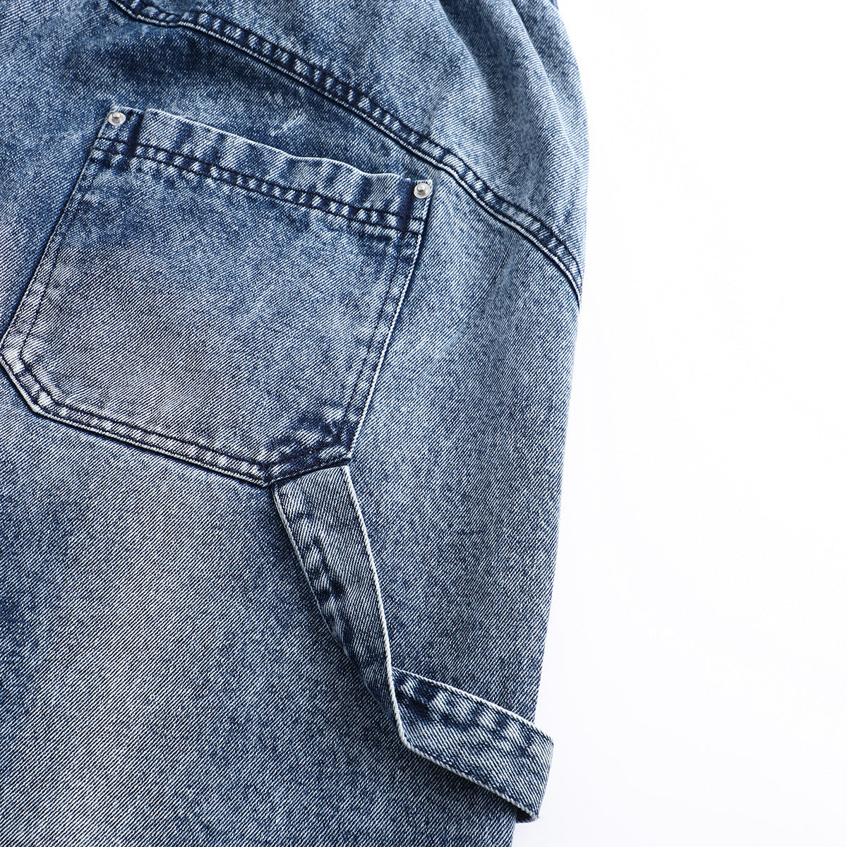 Close-up of a back pocket and turned-up cuff on blue acid-wash jeans.
