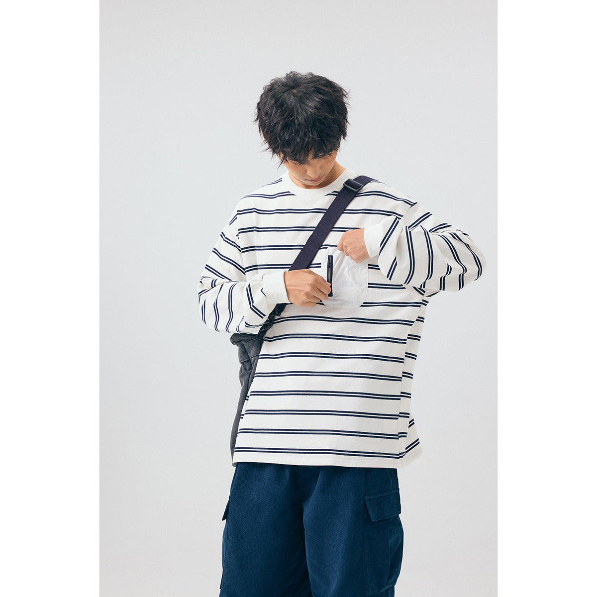 Model wearing a white long-sleeve shirt with navy horizontal stripes and a white zippered chest pocket.