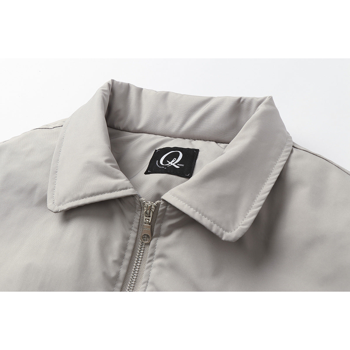 Close-up of a light gray jacket’s wide collar, sewn-in label, and front zipper.