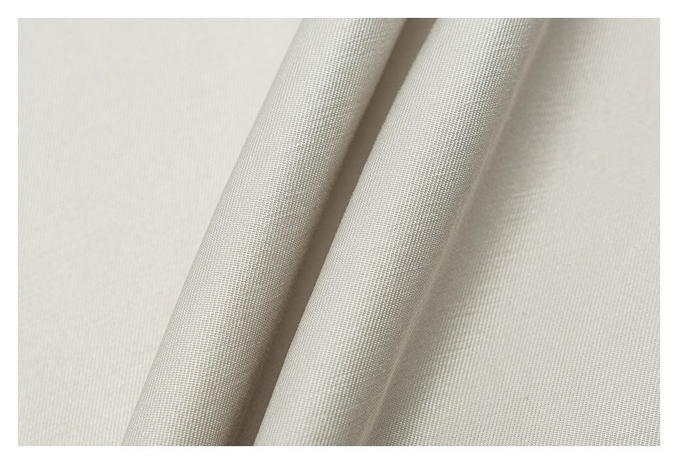 Close-up of light beige fabric folded to show its fine woven texture.