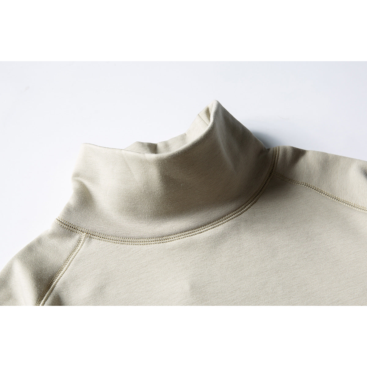 Close-up of a light beige high-neck sweatshirt showing the collar and raglan shoulder stitching.