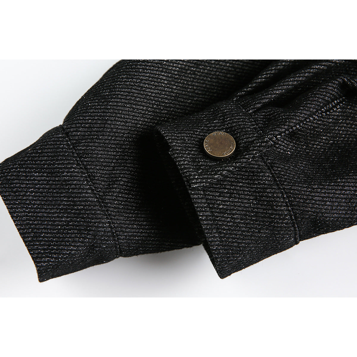 Close-up of a black textured jacket cuff and brass-tone button against a white background.