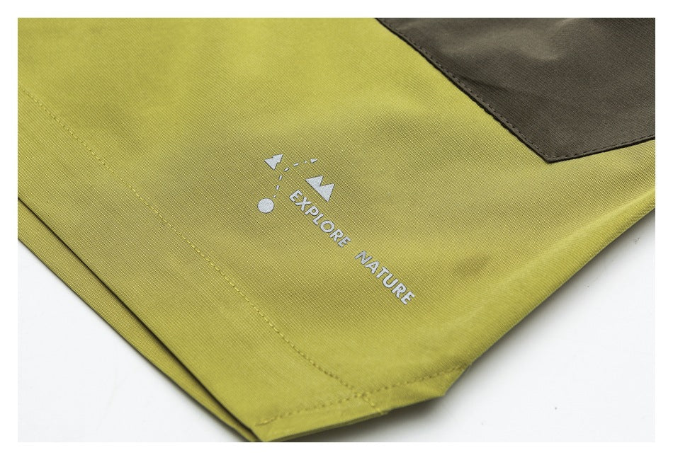 Close-up of yellow-green garment fabric with a dark patch, stitching, and a white “Explore Nature” print.