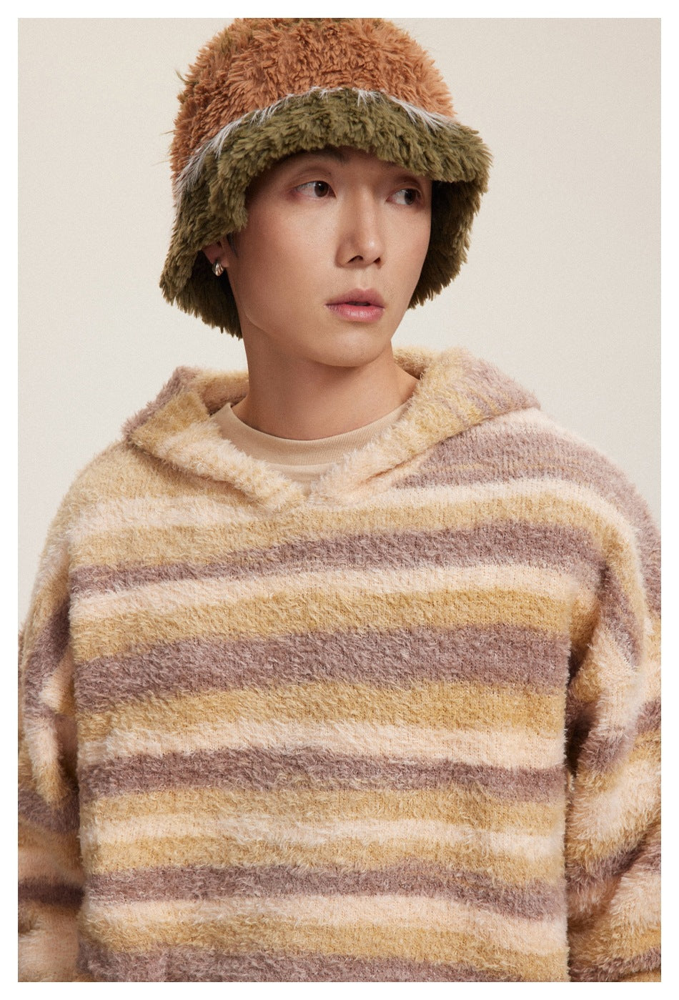 Close-up of a model wearing a fuzzy hooded pullover with cream, tan, and mauve stripes.
