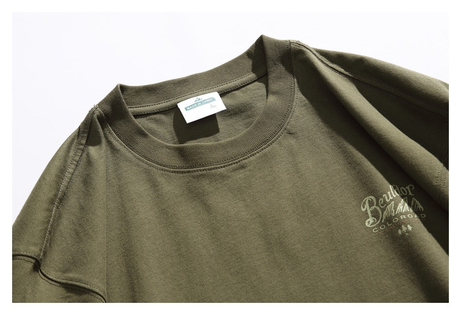 Close-up of an olive T-shirt neckline and small chest logo, with a visible neck label reading Made in China.
