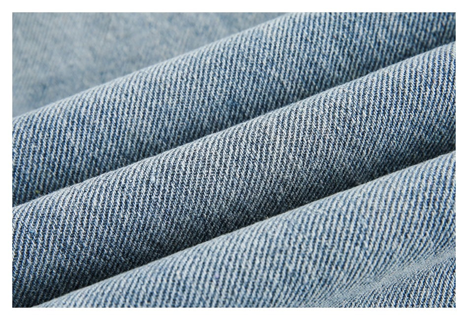 Macro view of folded blue denim showing its diagonal twill weave and contrasting fibers.