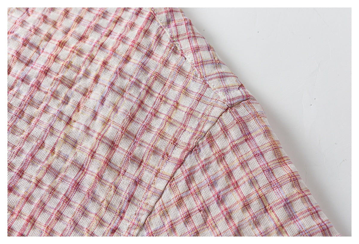Close-up of a shoulder seam on a cream shirt with pink and muted gold plaid.