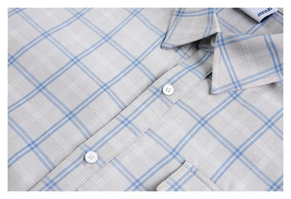 Close-up of the gray-and-blue plaid shirt front, showing its collar, white buttons, and pocket edge.