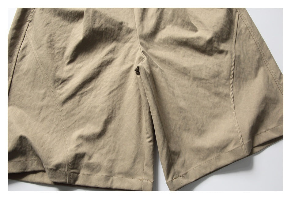 Close-up of the lower front of khaki shorts, showing the leg seams and hems.