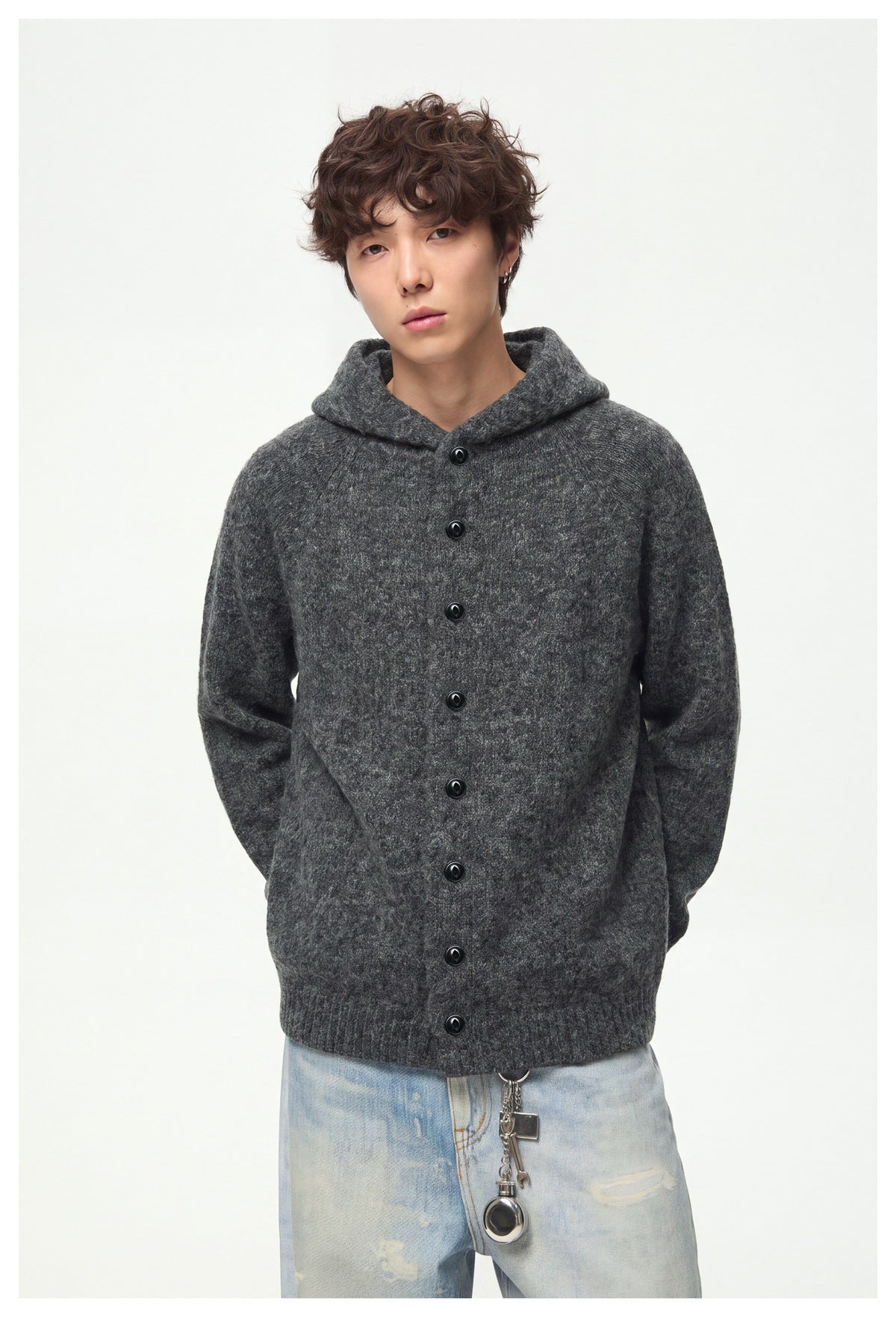 Front view of a model in a charcoal gray hooded cardigan with black buttons and light-wash jeans.
