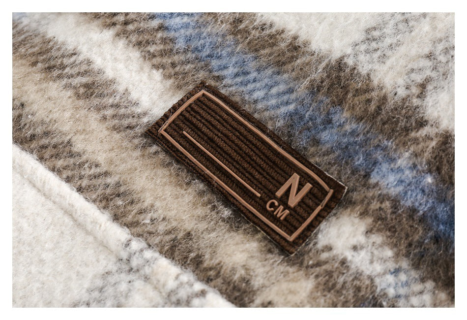 Close-up of fuzzy cream, taupe, brown, and muted blue plaid fabric with a small brown N CM patch.