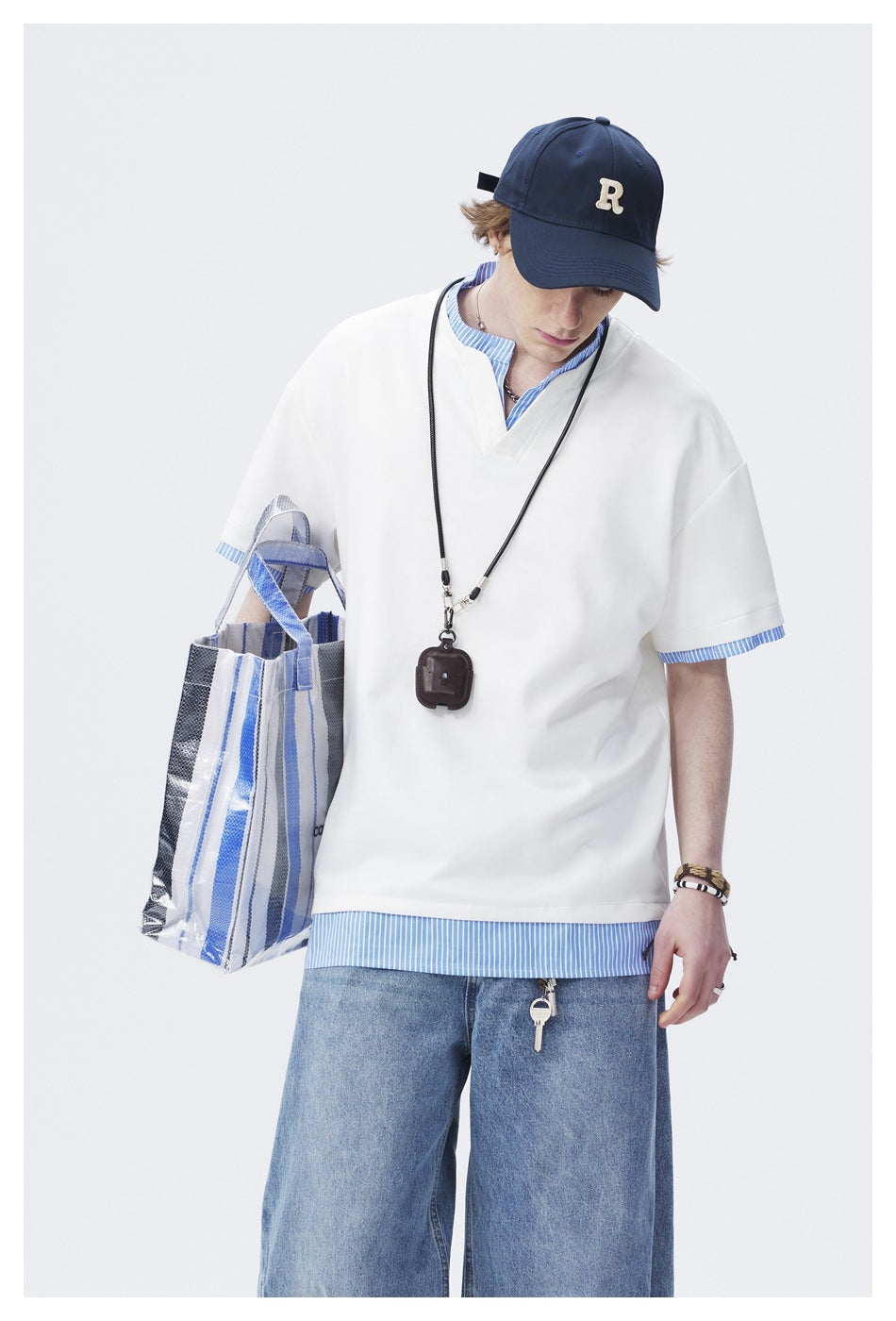 Closer view of a model wearing an oversized white V-neck tee over a blue-and-white striped shirt.