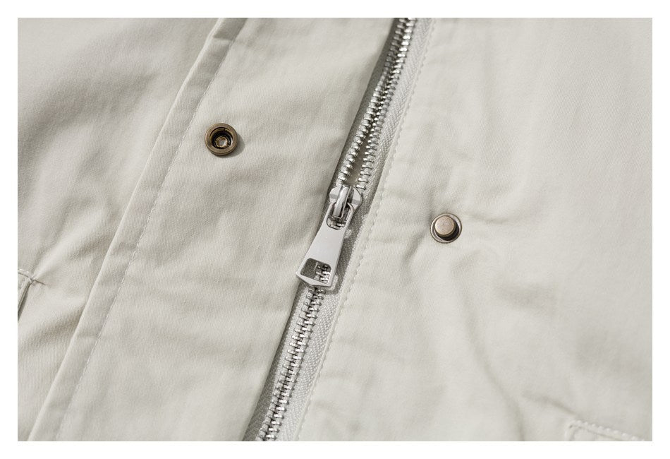 Close-up of the jacket's silver zipper and metal snap fasteners on off-white fabric.