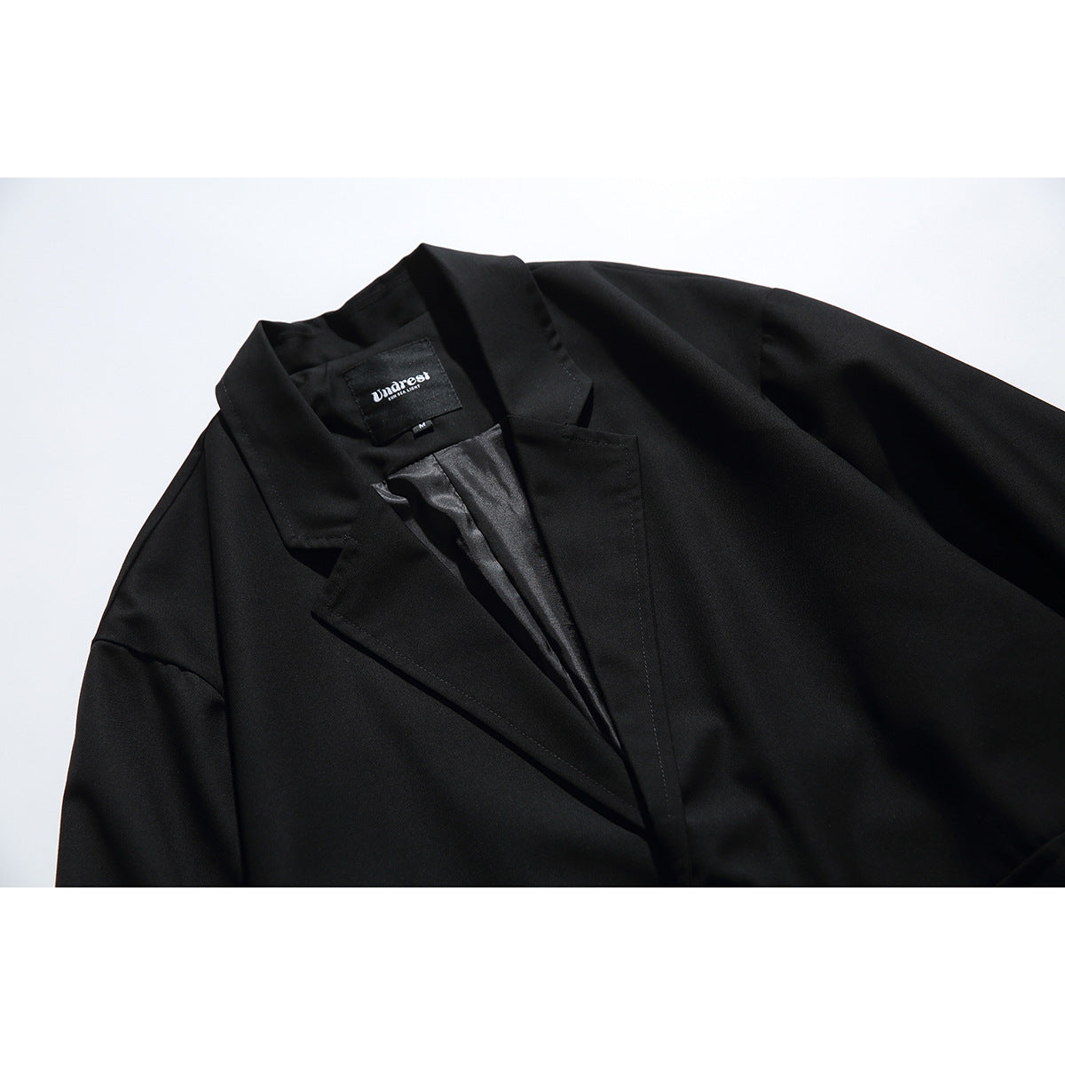 Close-up of a black blazer's notched lapel, collar, and shiny inner lining.