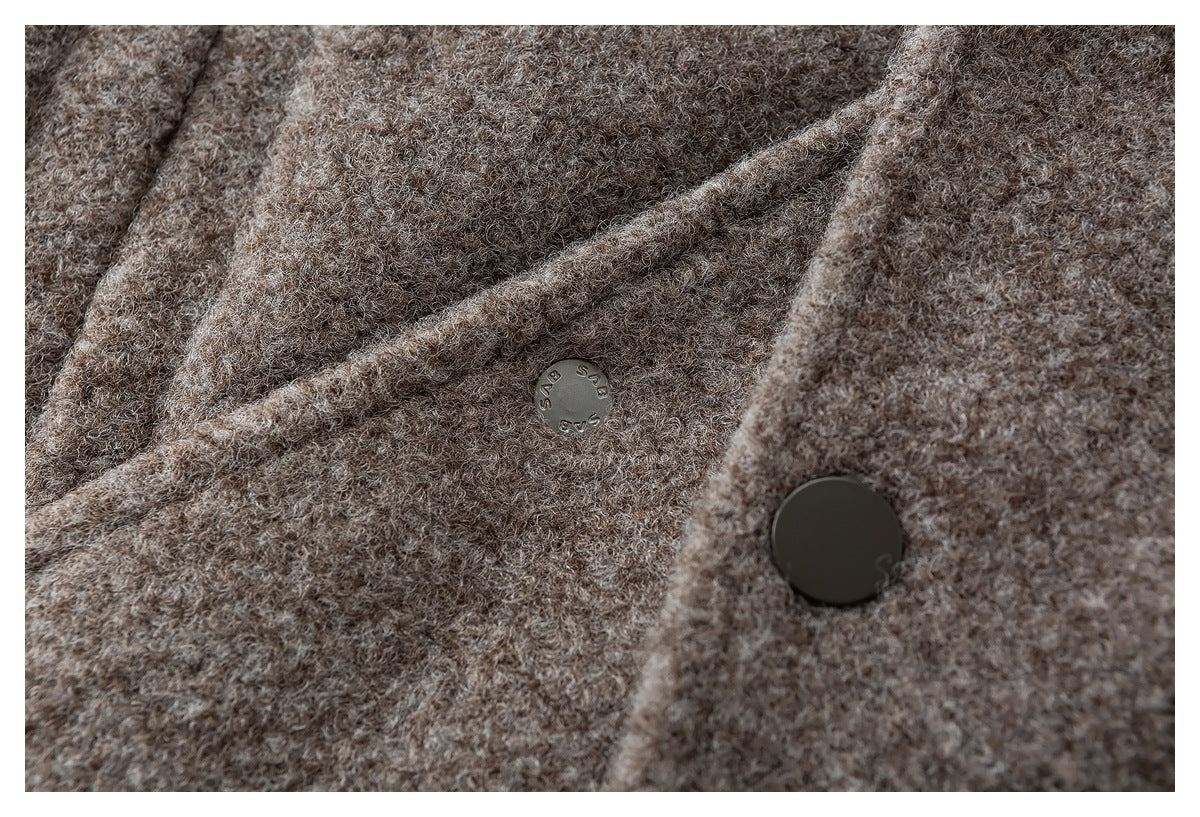 Close-up of taupe-brown curly fabric with a small engraved metal button and a larger dark button.