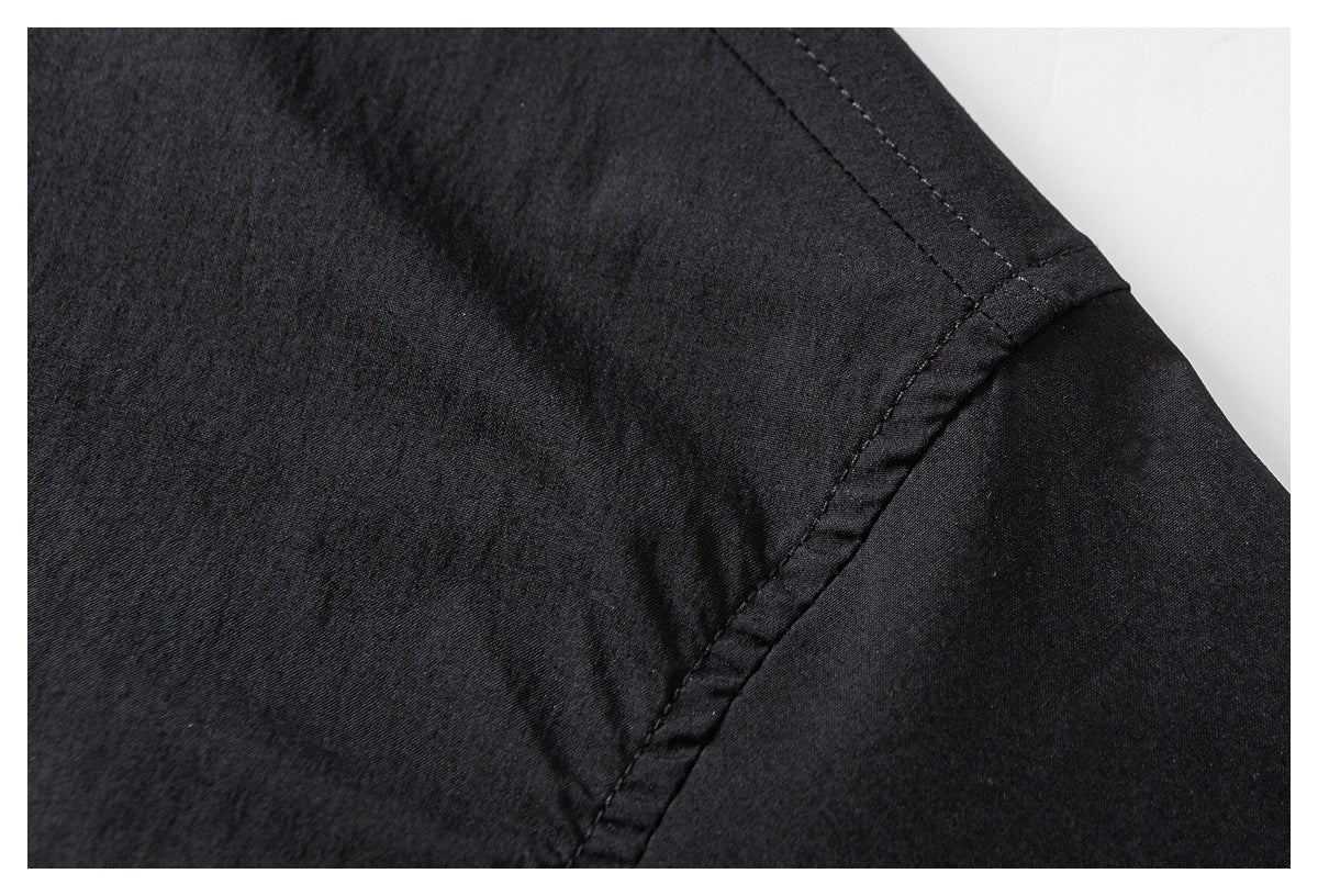 Close-up of black garment fabric showing a stitched seam joining textured and smooth panels.