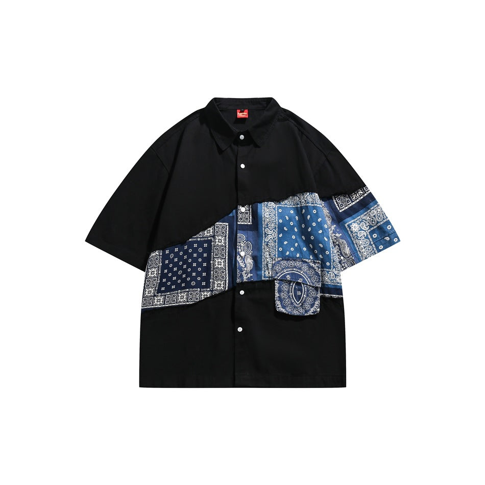 Black short-sleeve button shirt with diagonal blue bandana-paisley patchwork panel and flap pocket, front view