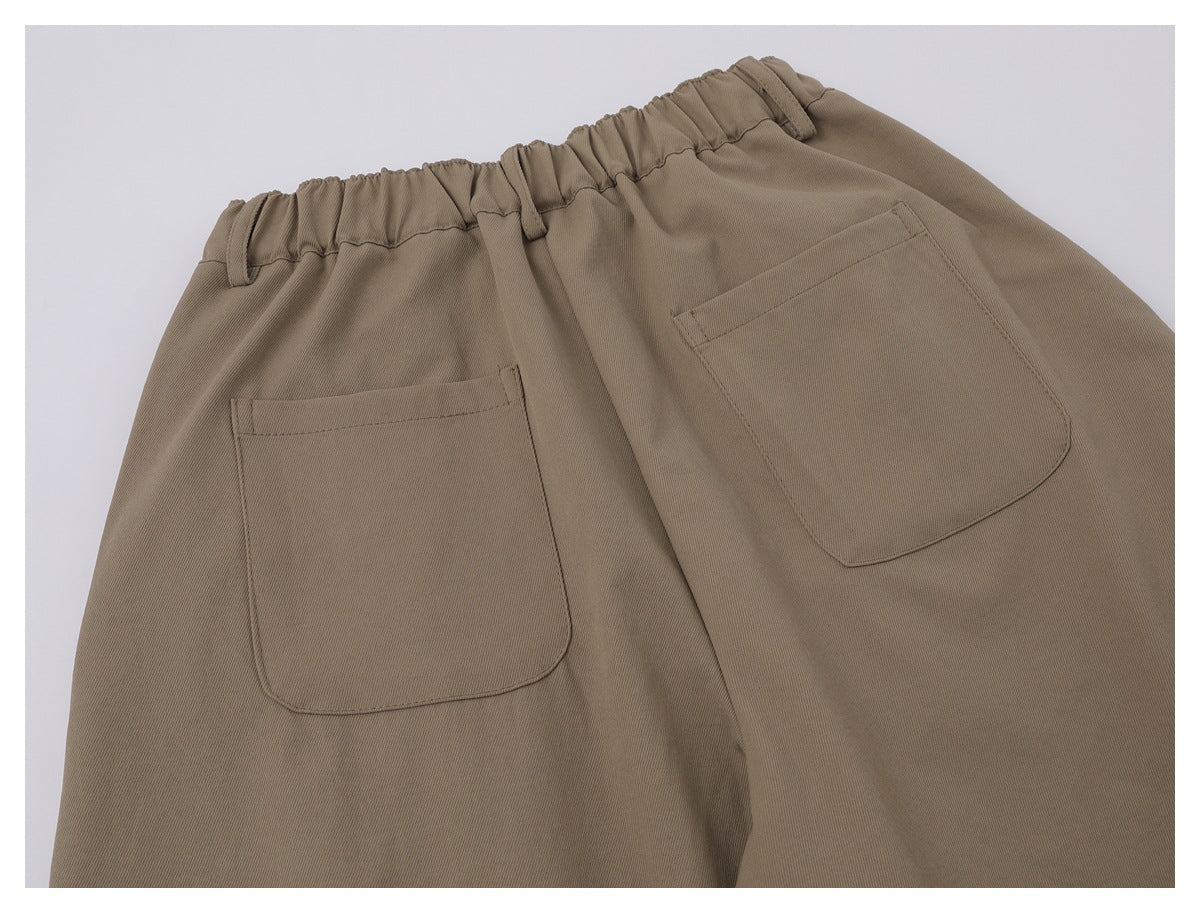 Cropped back view of taupe trousers with an elastic waist and two large patch pockets.