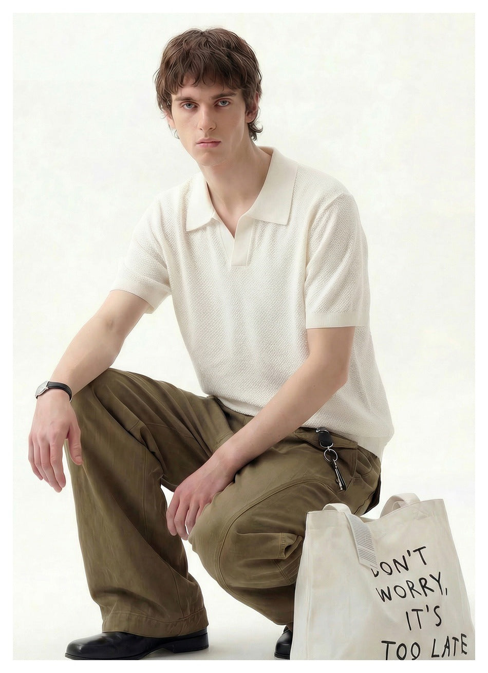 Seated man modeling an ivory textured short-sleeve polo and olive trousers.