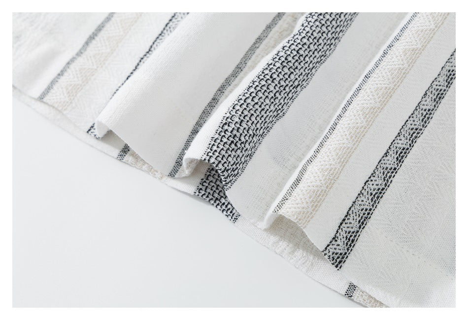 Close-up of the shirt's folded hem with alternating black, beige, and white woven stripes.