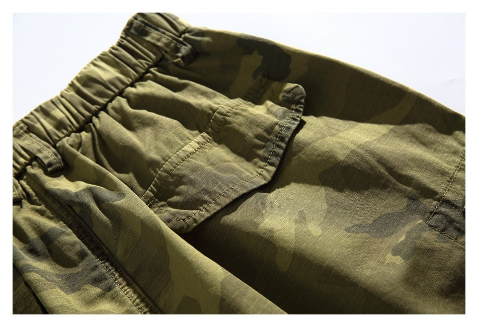 Close-up of a flap cargo pocket on olive camouflage shorts.