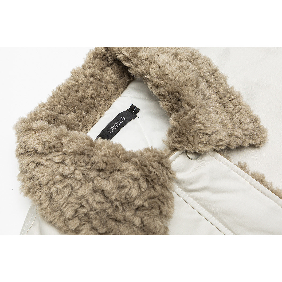 Close-up of a beige jacket's plush taupe collar, pale lining, and sewn neck label.