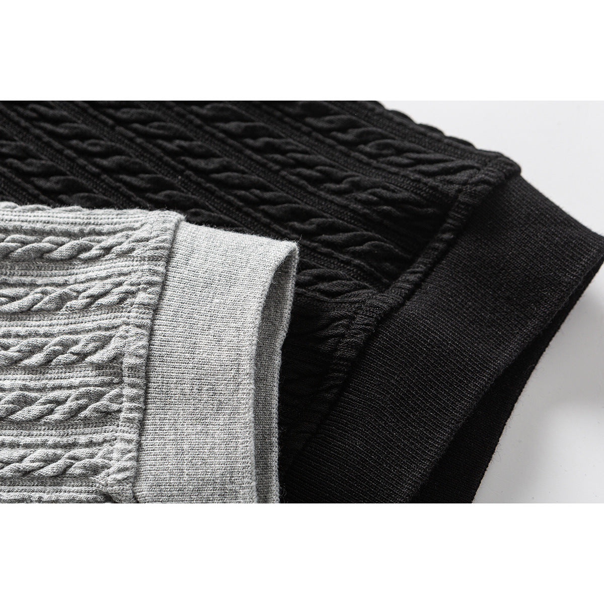 Close-up of gray and black cable-textured polo shirts showing their contrasting ribbed hems.