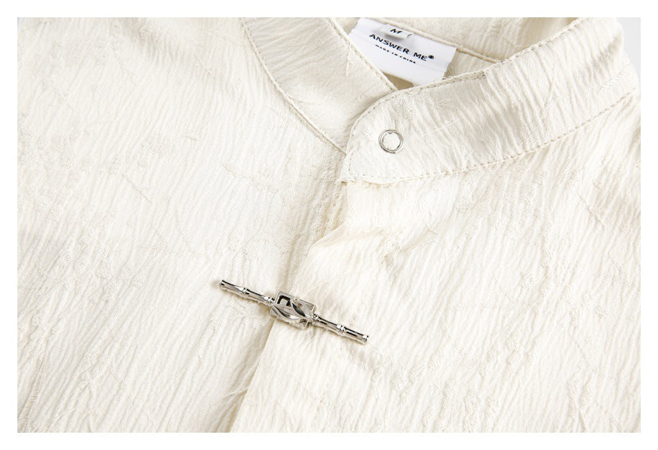 Ivory shirt close-up showing the stand collar, silver ring fastener, and decorative front bar closure.