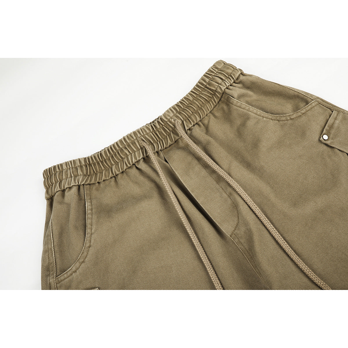 Close-up of khaki wide-leg pants showing the elastic waistband, drawstrings, and front pocket details.