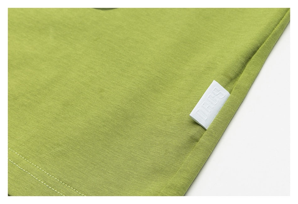 Close-up of lime-green garment fabric and its stitched edge, with a small white woven label.
