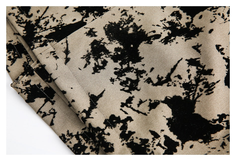 Close-up of beige fabric with an irregular black floral pattern and a folded edge.