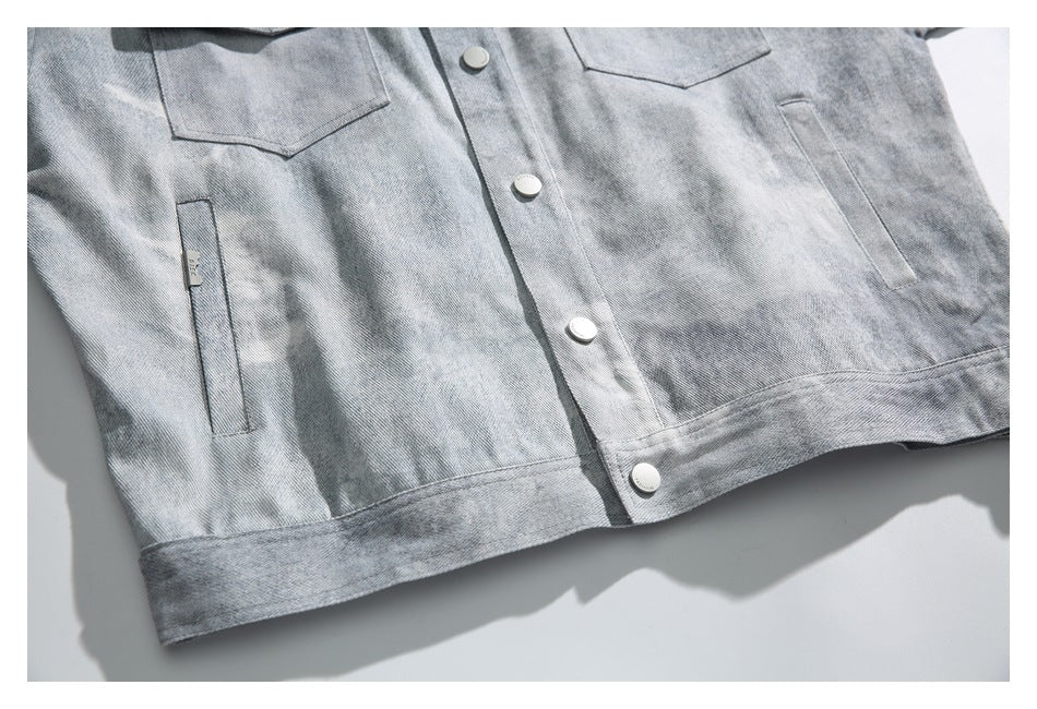 Cropped flat lay of a light gray denim jacket front with button placket, chest pockets, and side pockets.