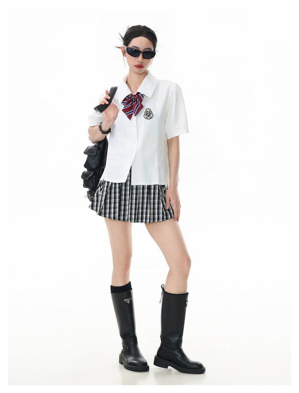 Full-length model wearing a white shirt with a striped bow, plaid skirt, and black knee-high boots.