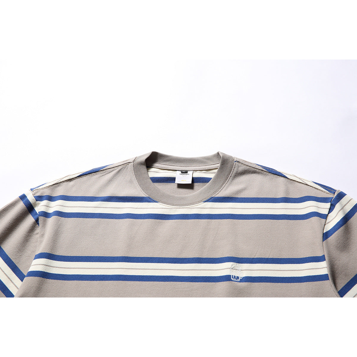 Close view of a taupe crew-neck T-shirt with blue and ivory horizontal stripes and a small embroidered chest emblem.