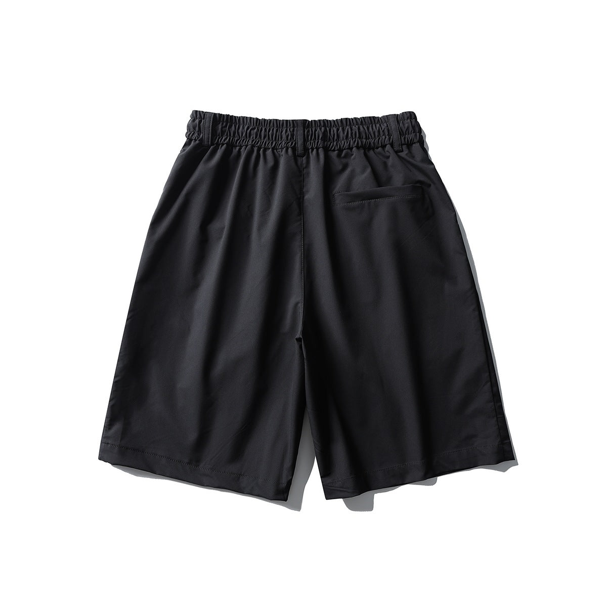 Back view of black shorts with a gathered elastic waistband, belt loops and a single welt pocket.